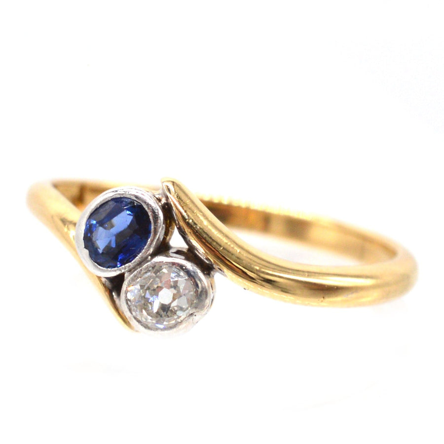 Edwardian 18ct gold crossover ring featuring sapphire and diamond, symbolizing love and connection.