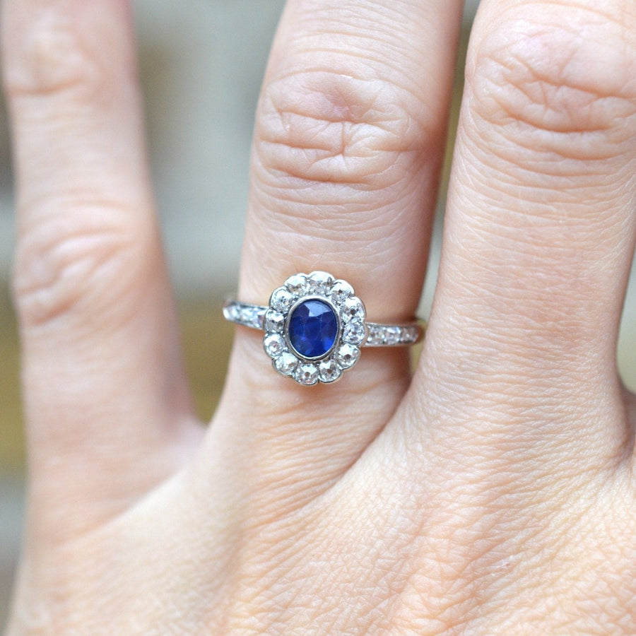 Edwardian 18ct gold sapphire and diamond cluster ring showcased on a hand, featuring a vibrant royal blue sapphire.