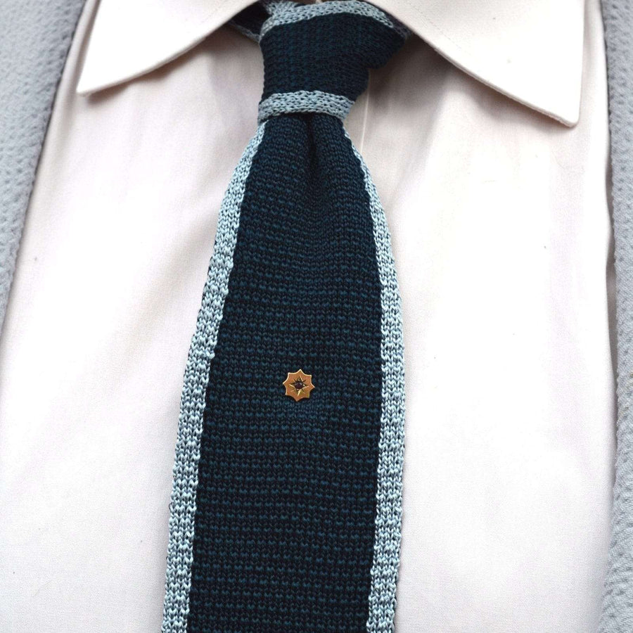 Edwardian 9ct gold and ruby tie pin displayed on a colorful knitted tie, showcasing its classic elegance.