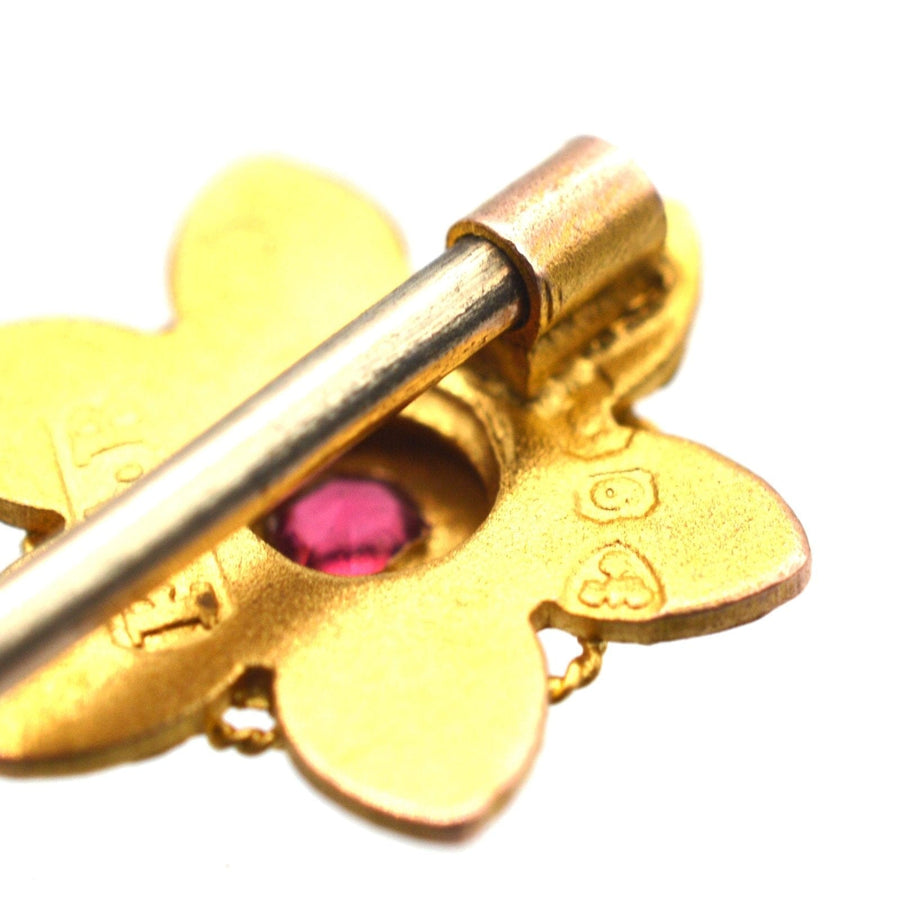 Close-up of an Edwardian 9ct gold flower tie pin featuring a ruby gemstone, showcasing intricate craftsmanship.