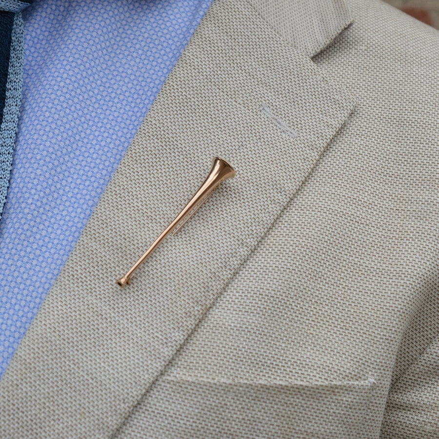Edwardian 9ct gold hunting horn brooch displayed on a beige blazer lapel, showcasing its quirky design.