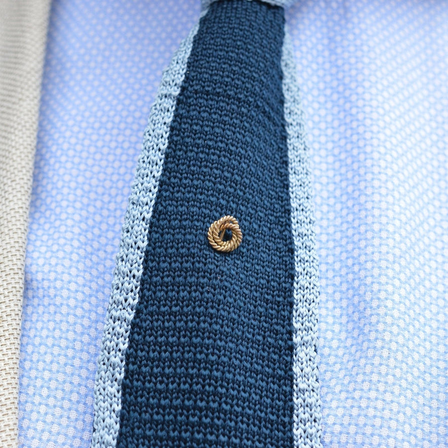 Edwardian 9ct gold double knot rope tie pin worn on a blue knitted tie, symbolizing love and commitment.