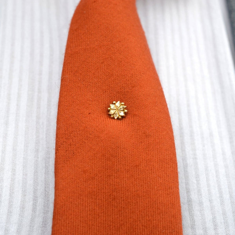 Edwardian gold plated star tie pin on a stylish orange silk tie, enhancing sophistication and elegance.