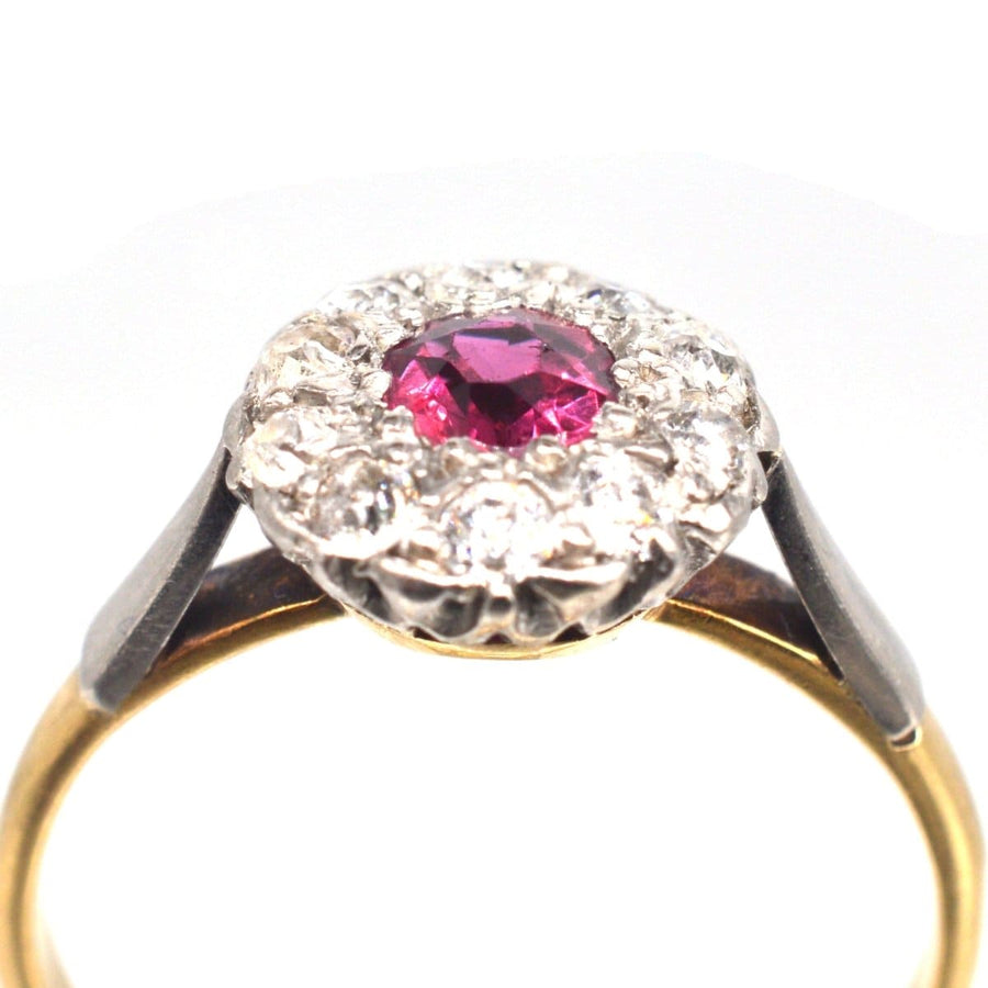 Edwardian platinum and gold cluster ring featuring a natural ruby and diamond halo.