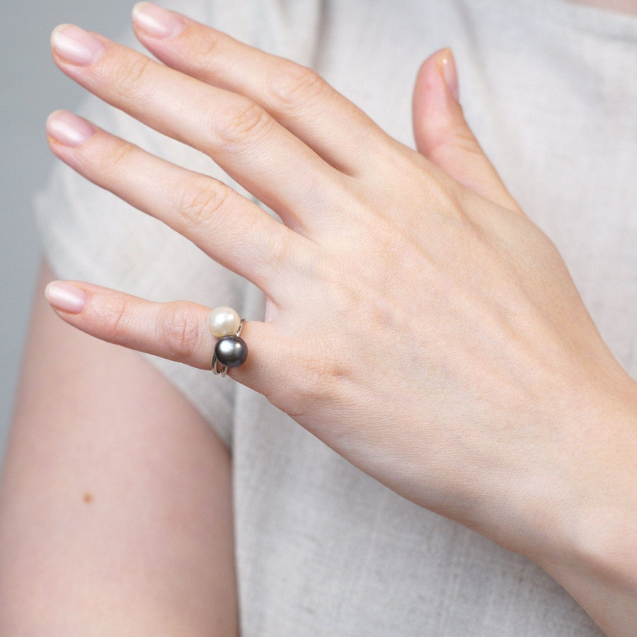 Elegant hand showcasing Edwardian platinum ring with natural black and white saltwater pearls.