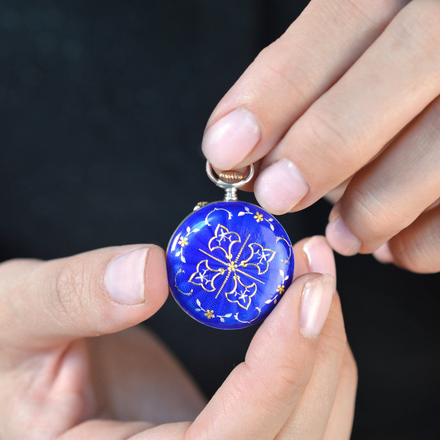 Person holding an Edwardian silver pocket watch with royal blue guilloché enamel and floral design.