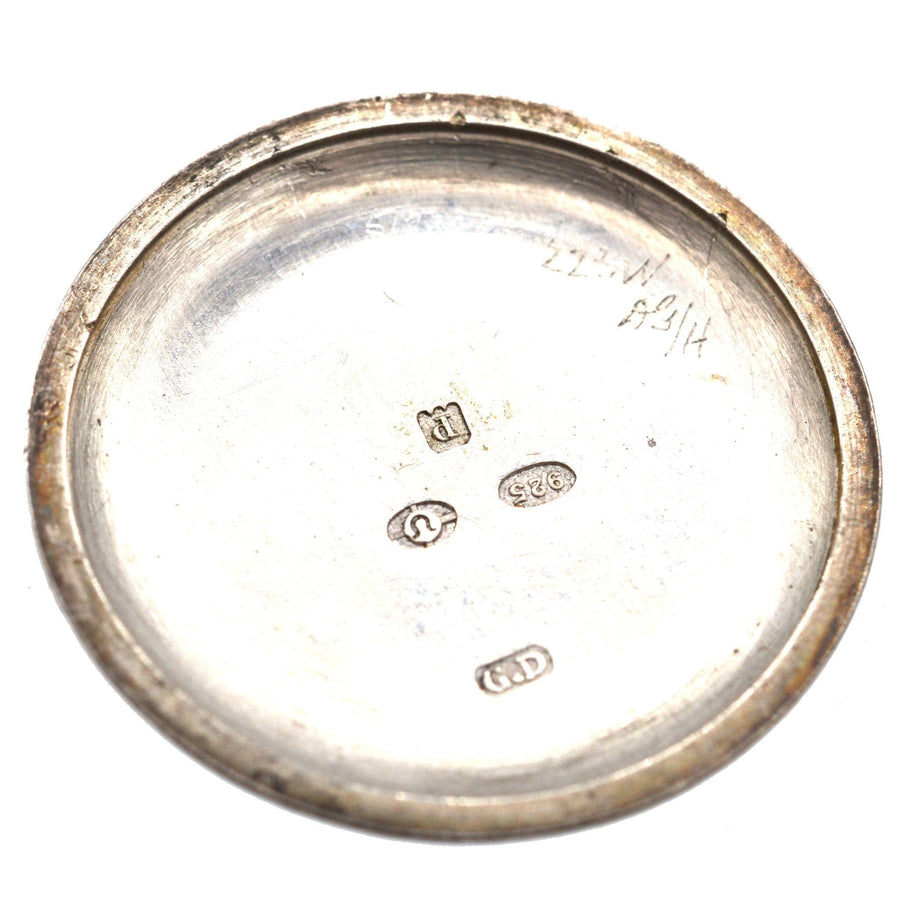 Back view of an Edwardian silver watch case, showing engravings and hallmarks, vintage craftsmanship details.