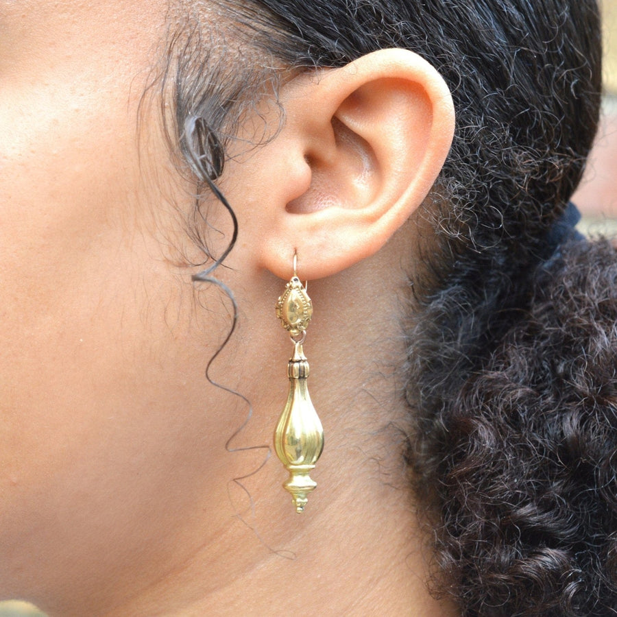Close-up of a person wearing 19th century 18ct gold drop earrings, showcasing elegant vintage design.
