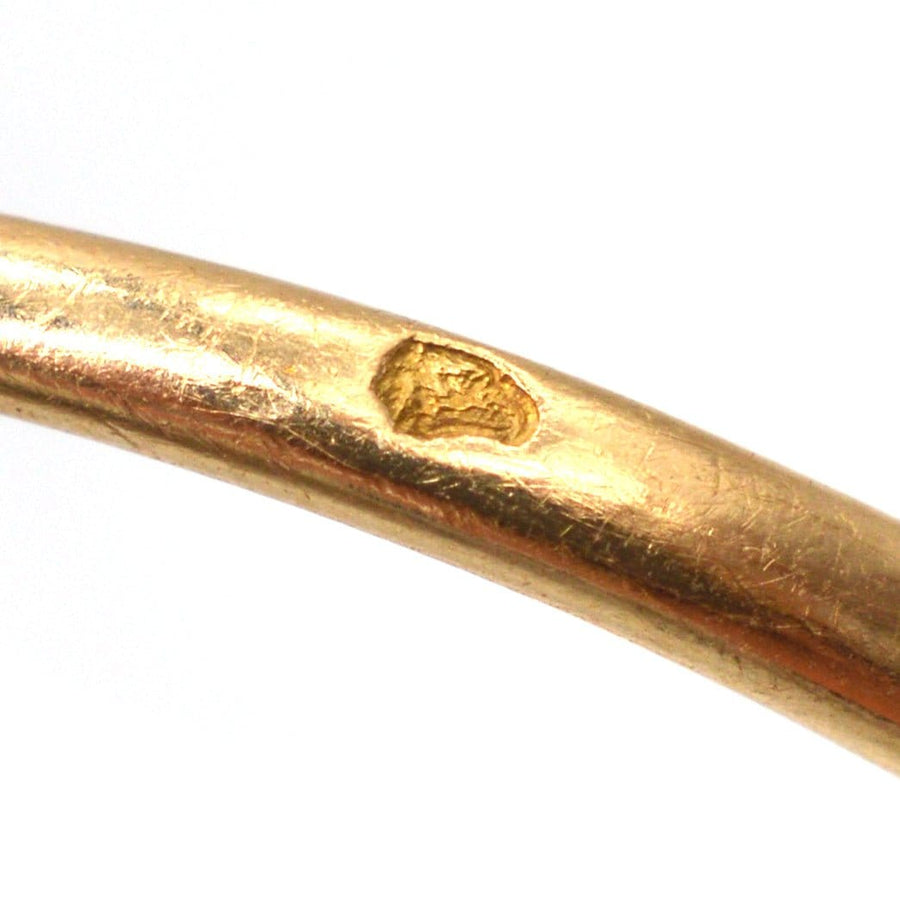 Close-up of a gold ring showing a detailed marking on the band, highlighting unique craftsmanship and character.