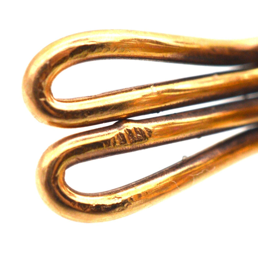 Close-up of intricately designed gold earring clips showcasing elegant, flowing curves and polished finish.