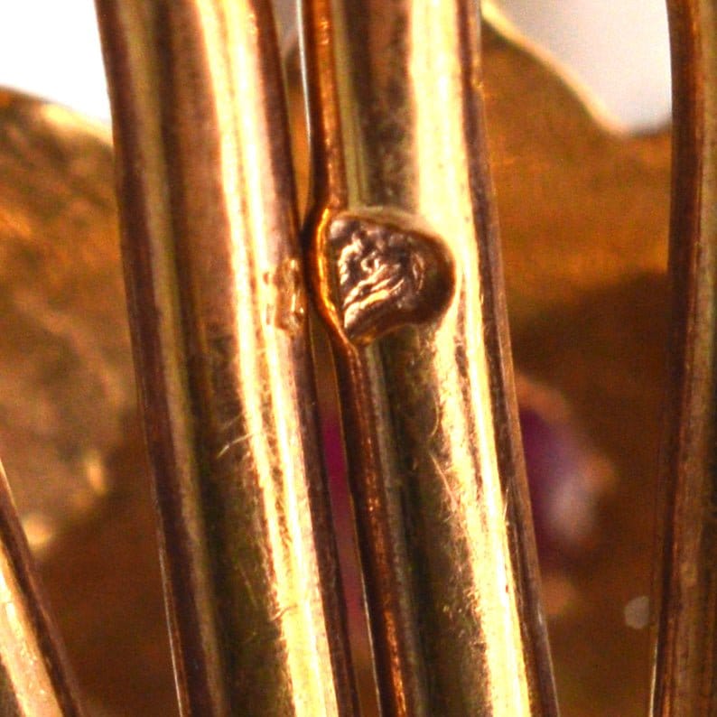 Close-up of hallmark on 18ct gold scallop shell clip-on earrings showcasing fine craftsmanship.