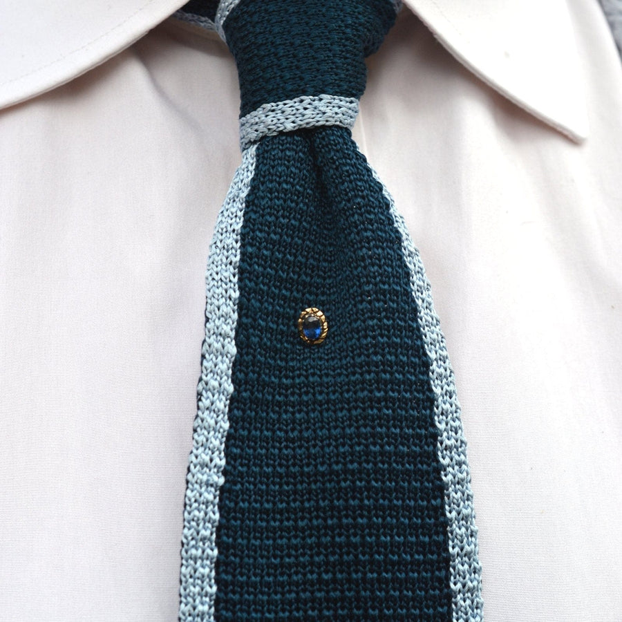 Georgian 15ct gold sapphire tie pin on a stylish blue silk tie, featuring intricate repoussé design