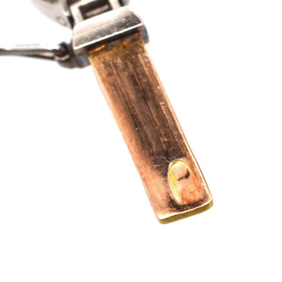 Close-up of an antique bracelet clasp showing gold, platinum, and hallmark details from early 20th century.