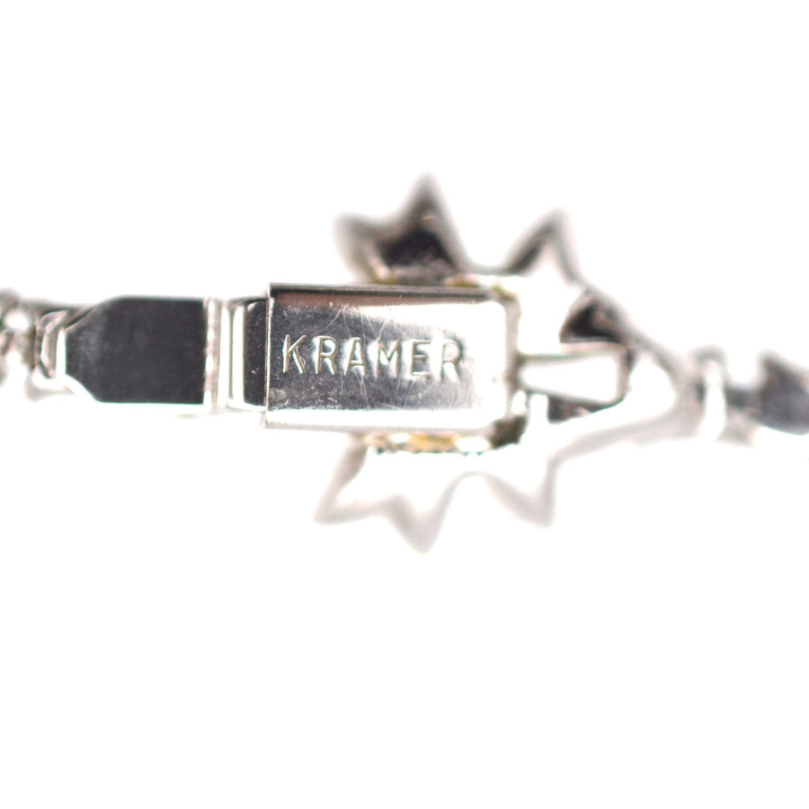 Close-up of Kramer signature on a vintage 1950s necklace, featuring silver-tone rhodium plating and intricate design.