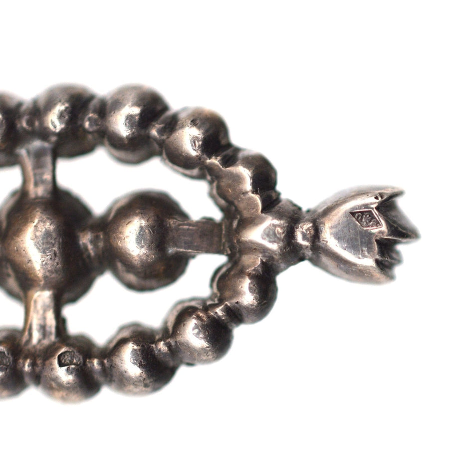 Close-up of large silver Portuguese style earring, featuring articulated design and elegant vintage detail.