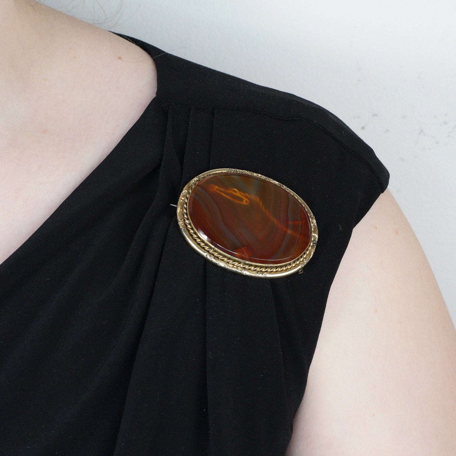 Large Scottish Victorian 9ct gold banded agate brooch on a black dress shoulder, showcasing its stunning natural patterns.