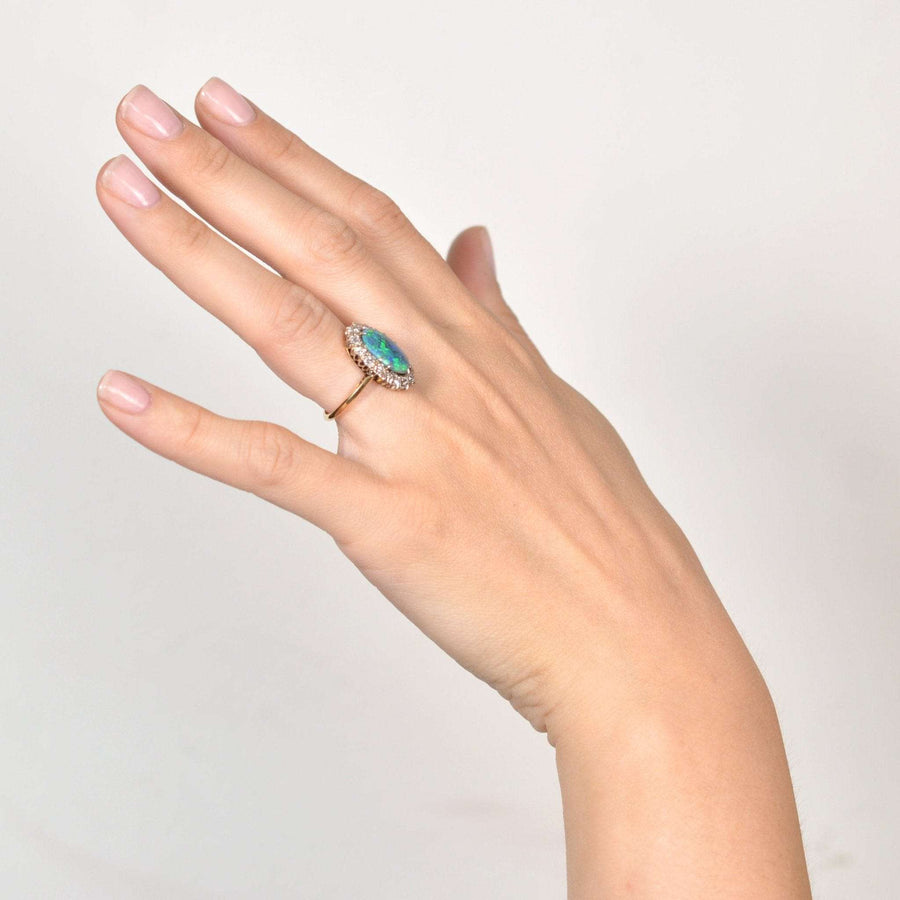 Hand wearing a large Victorian 18ct gold ring featuring a stunning black opal and diamond cluster design.