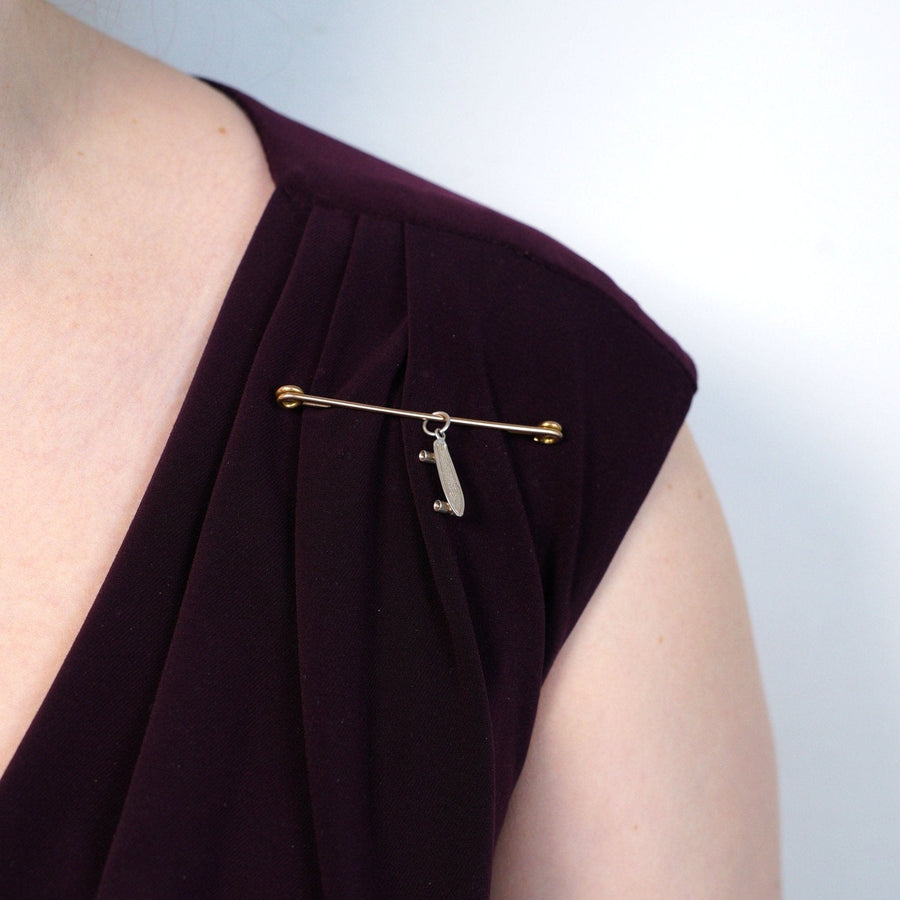 Large Victorian 9ct gold safety pin brooch worn on a burgundy dress, showcasing its elegant design and historical significance.