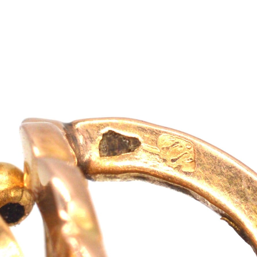Close-up of 19th-century 18ct gold mini hoop earrings showing horse head hallmark and hinge back fitting.