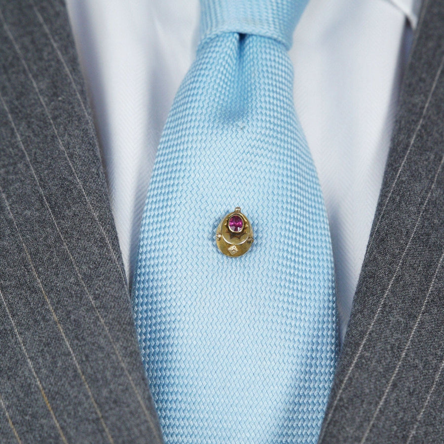 Late Victorian 15ct gold tie pin with red paste 'ruby' on a light blue tie, showcasing elegant vintage style.