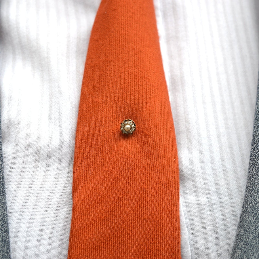 Late Victorian 15ct gold natural pearl and diamond cluster tie pin on an orange silk tie.