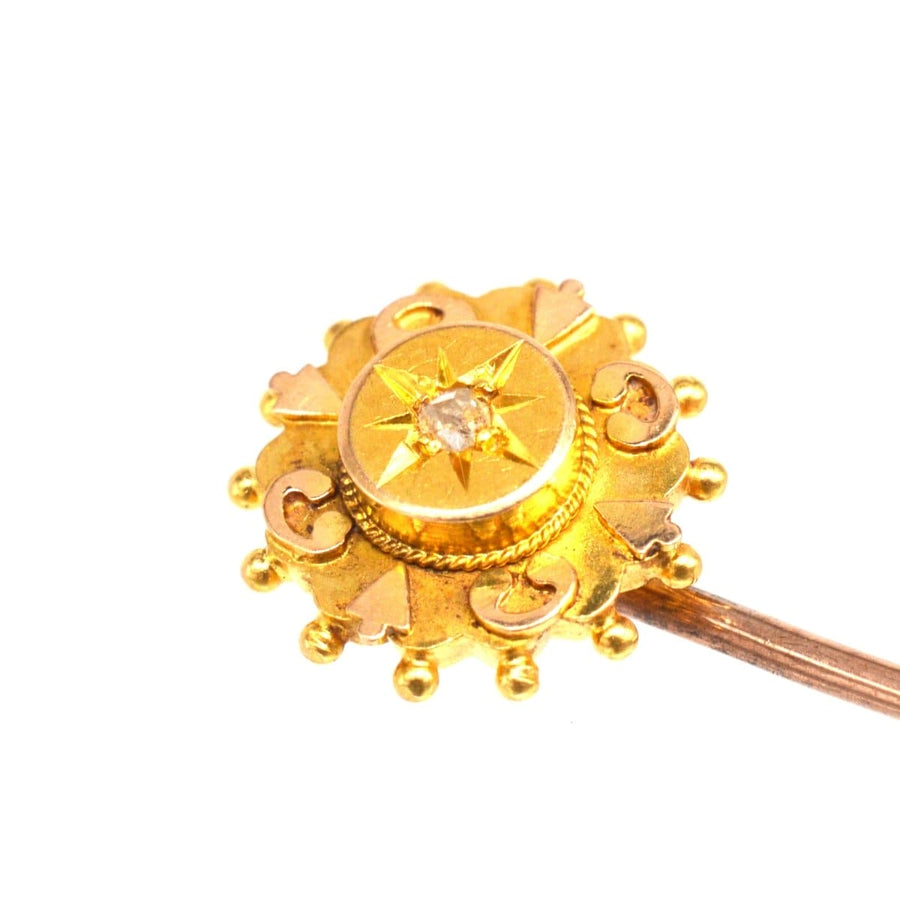 Close-up of a late Victorian 15ct gold star tie pin with old cut diamond and intricate details.