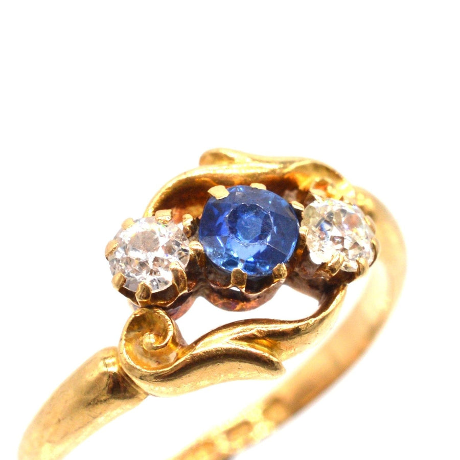 Late Victorian 18ct gold crossover ring with sapphire and diamond three stone centerpiece, intricately carved design.