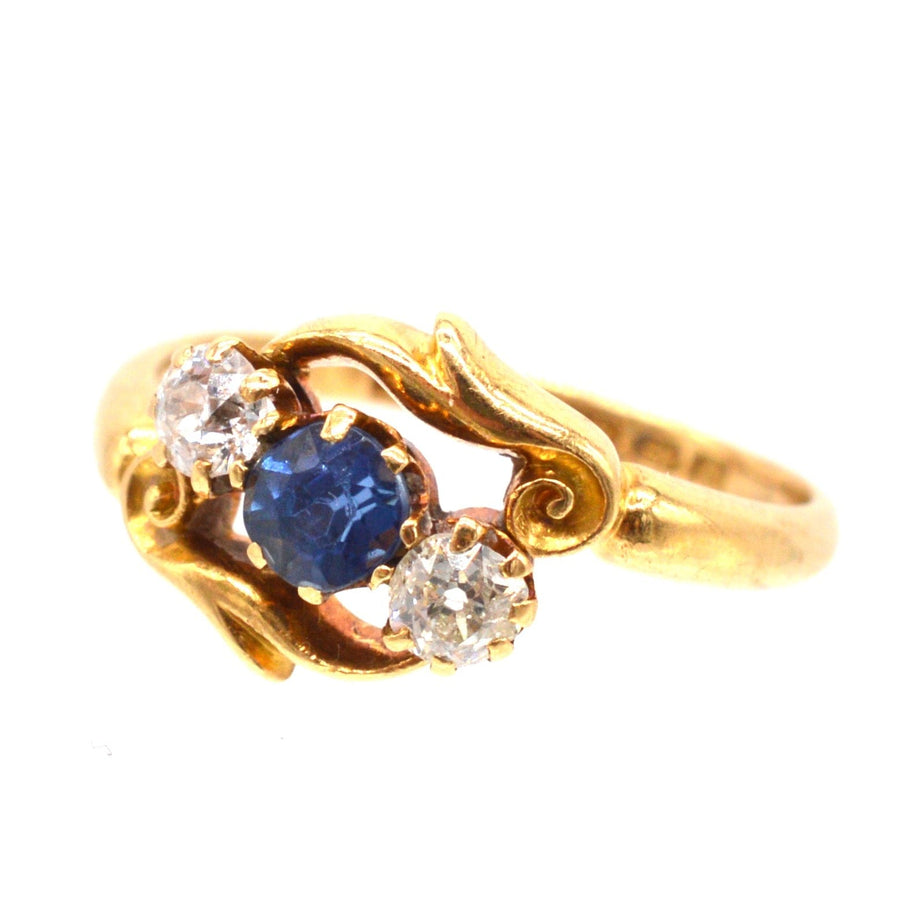 Late Victorian 18ct gold crossover ring featuring sapphire and diamond three stone design with intricate carvings.