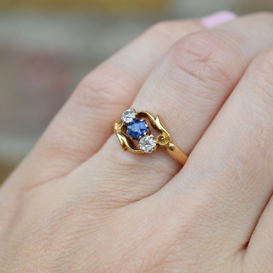 Late Victorian 18ct gold crossover ring featuring sapphire and diamond, intricately carved design, ideal engagement ring.