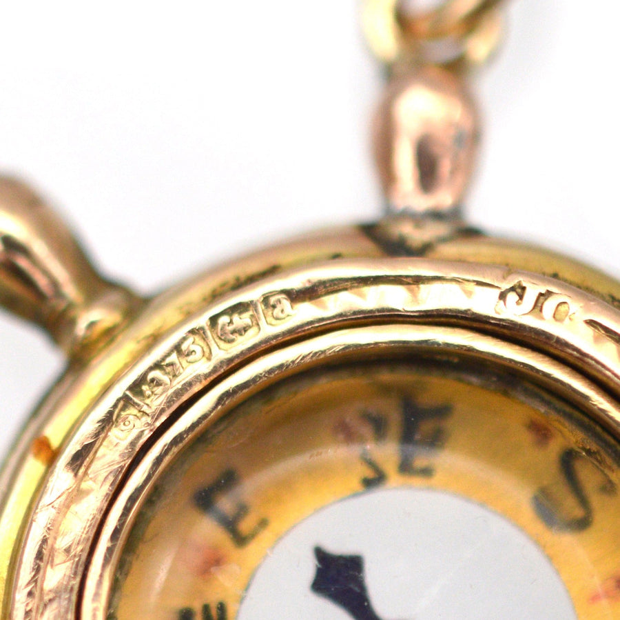 Close-up of a 9ct gold ship wheel compass pendant with maker's mark JC, dating from 1900 Birmingham.