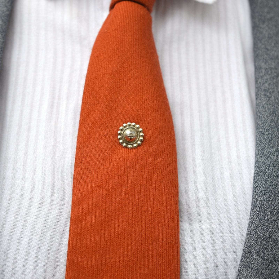 Late Victorian silver tie pin on an orange silk tie, enhancing the elegant look with a stylish design.