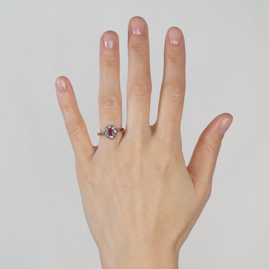 Late Victorian silver and rose gold ruby and diamond cluster ring on a hand, circa 1890s.