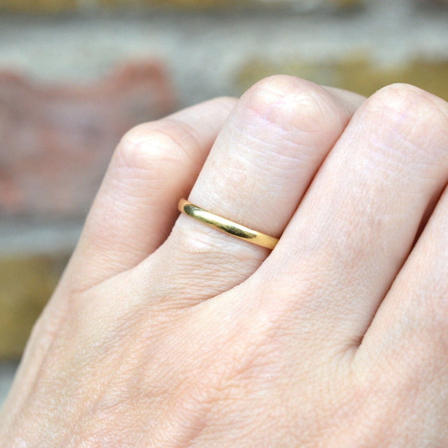Modern 18ct gold wedding ring worn on hand, 2mm plain band, perfect for stacking or as a wedding band.