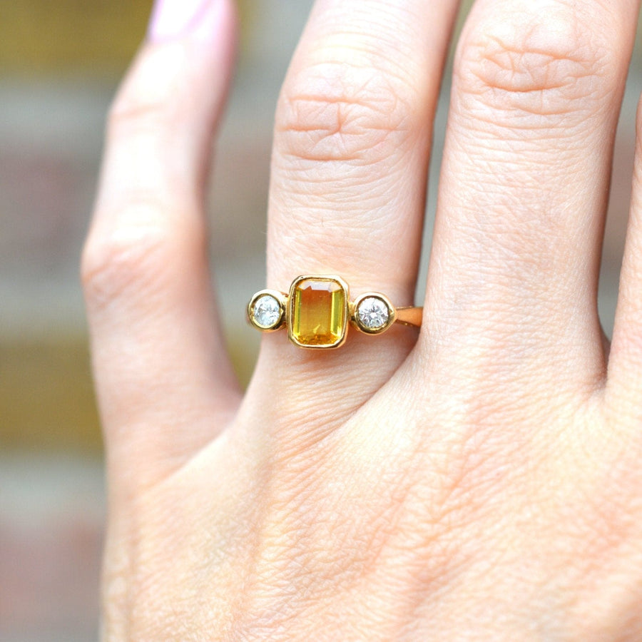 Modern 18ct gold ring featuring a golden yellow sapphire and two white diamonds, perfect for an engagement.
