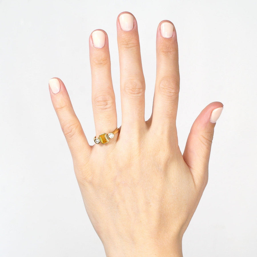 Modern 18ct gold, yellow sapphire and diamond three stone ring worn on a hand.