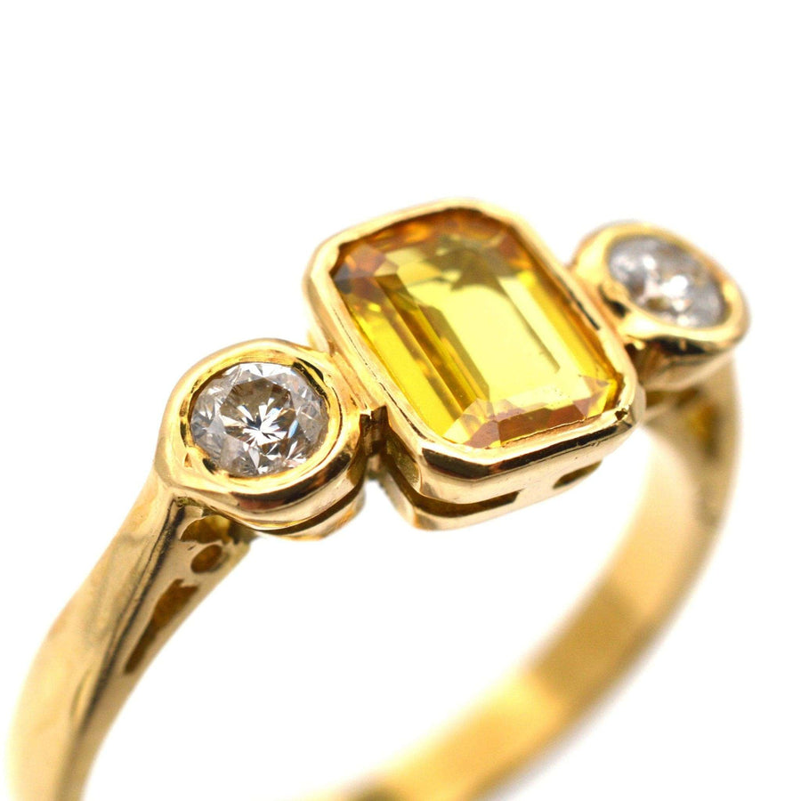 Modern 18ct gold three stone ring featuring a yellow sapphire flanked by two brilliant white diamonds.