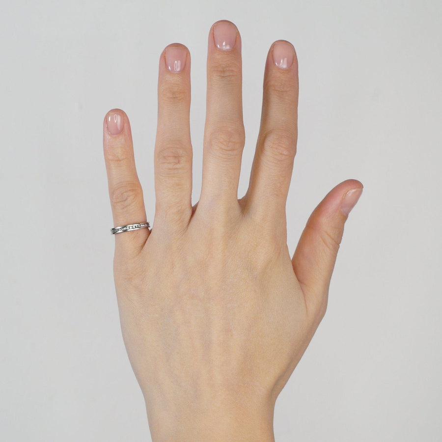 Modern 18ct white gold diamond channel setting eternity ring worn on a woman's hand.