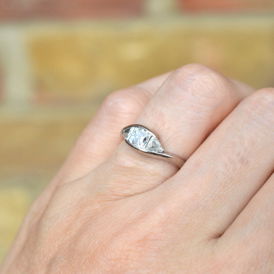 Modern 18ct white gold three stone diamond ring on hand featuring GIA certified cushion cut diamond.