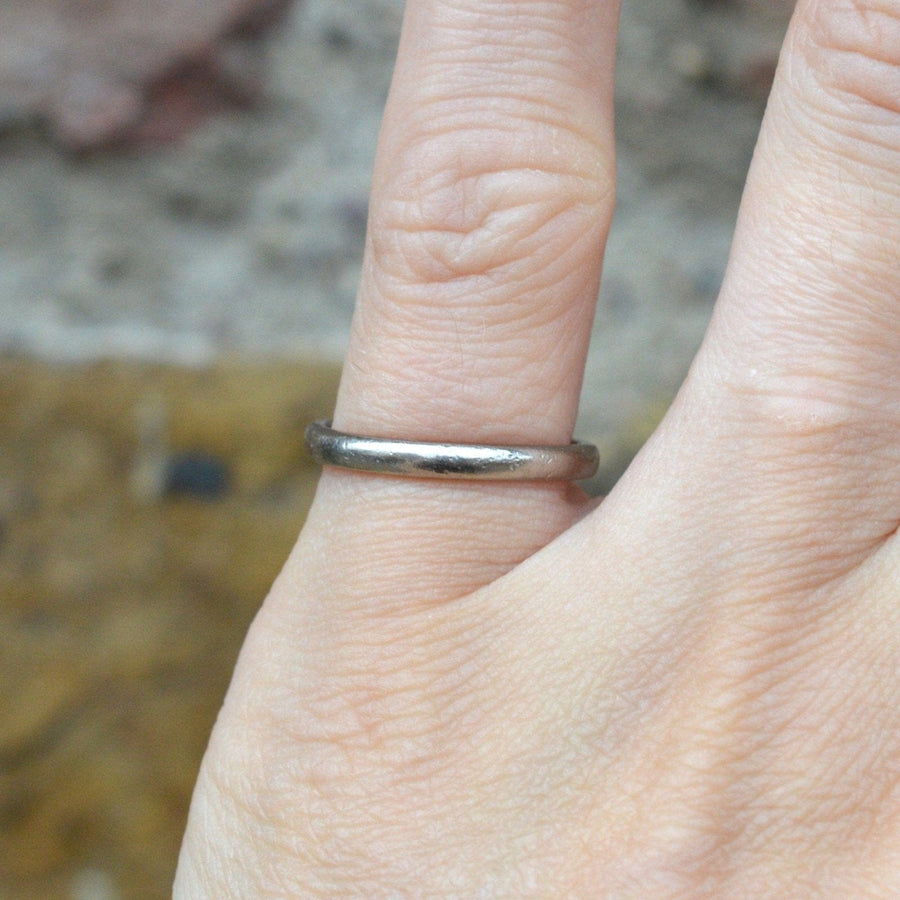 Simple 18ct white gold wedding ring displayed on a finger, showcasing its plain band design.