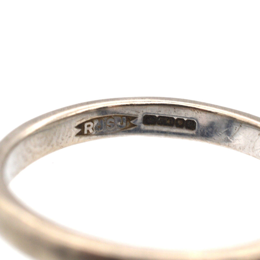 Close-up of a modern 18ct white gold wedding ring band with hallmark, showcasing its simple and elegant design.