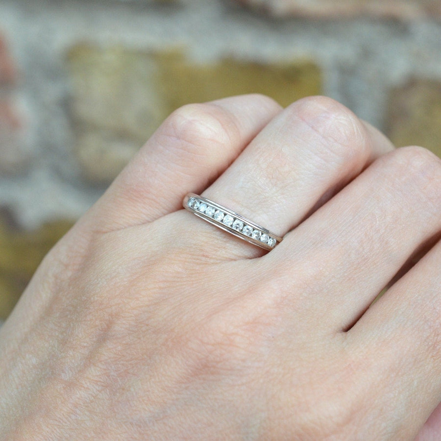 Hand wearing a 9ct white gold diamond half eternity ring, showcasing brilliant cut diamonds in a sleek channel setting.