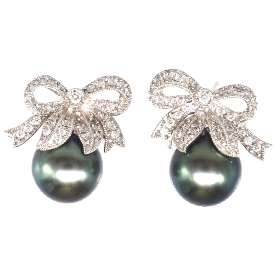 Modern diamond bow and Tahitian black pearl stud earrings, elegant and chic for timeless style.