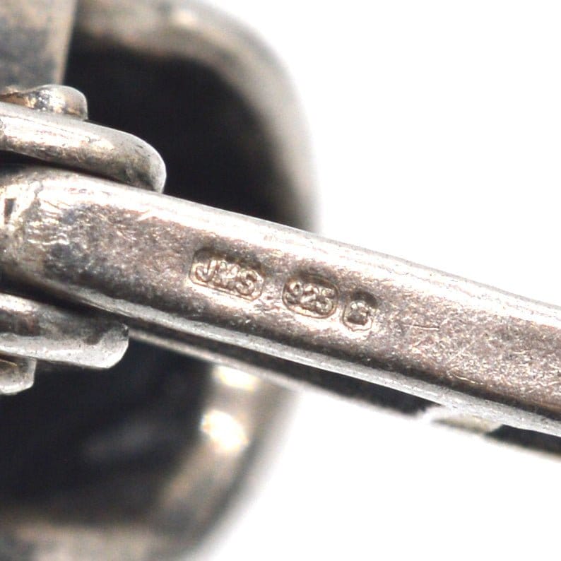 Sterling silver skull cufflinks with oxidised detail, showcasing quality marking close-up.