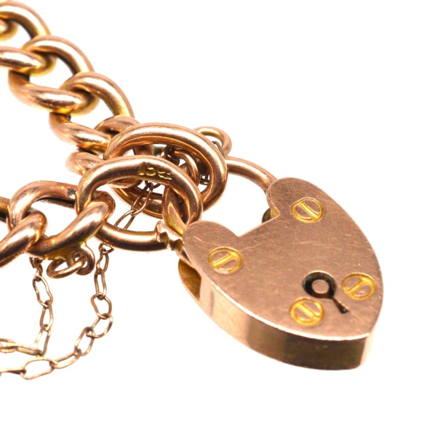 Close-up of a 15ct gold child's curb bracelet featuring an opening heart lock from the Edwardian era.