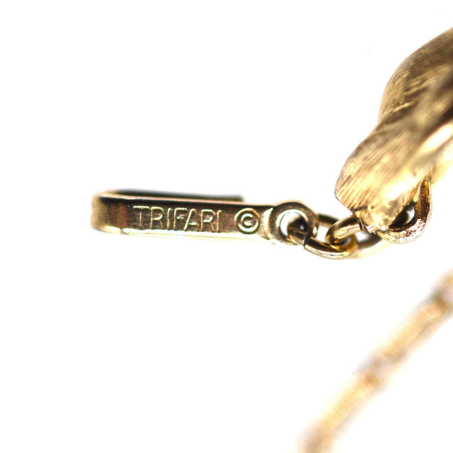 Close-up of Trifari hallmark on gold-tone jewelry clasp, showcasing vintage 1950s craftsmanship.