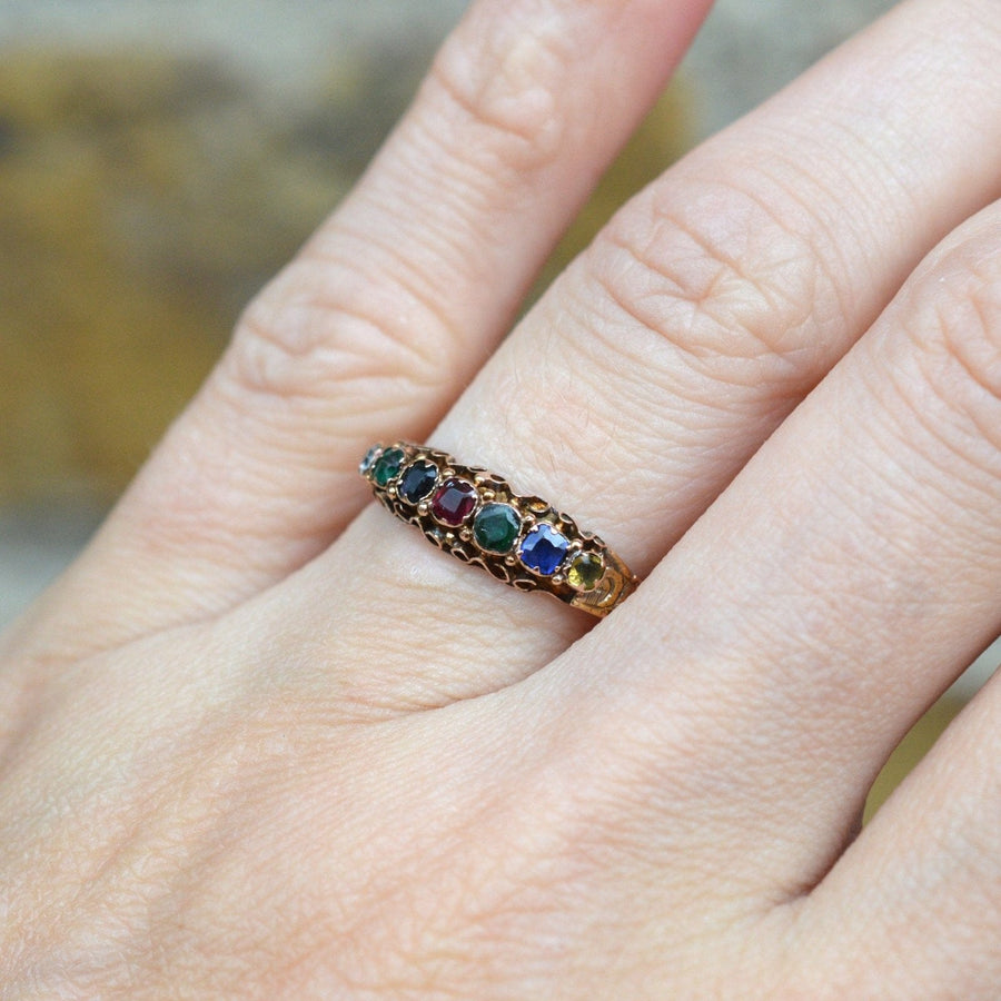 Victorian 15ct gold acrostic ring with colorful stones spelling 'Dearest', worn on a hand.