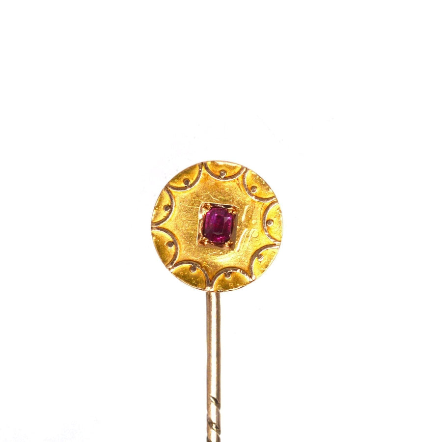 Victorian 15ct gold circle tie pin featuring a natural ruby, adorned with intricate gold swirls, from the 1880s.