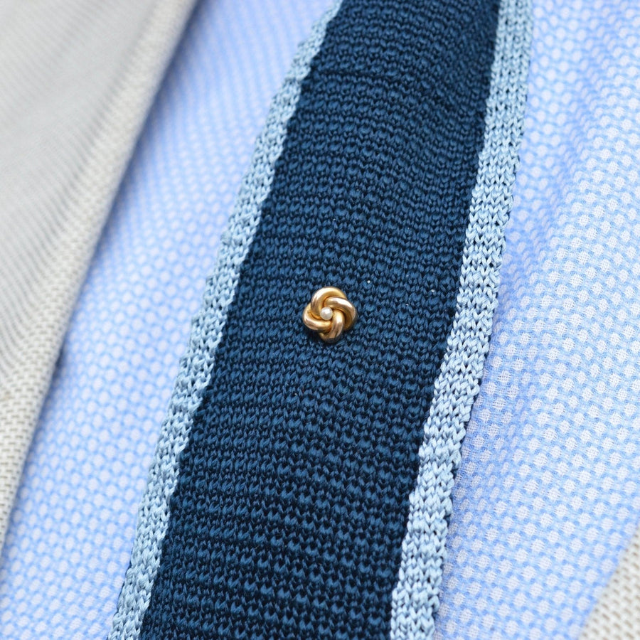 Victorian 15ct gold knot and pearl tie pin on a textured tie, symbolizing everlasting love and timeless elegance.