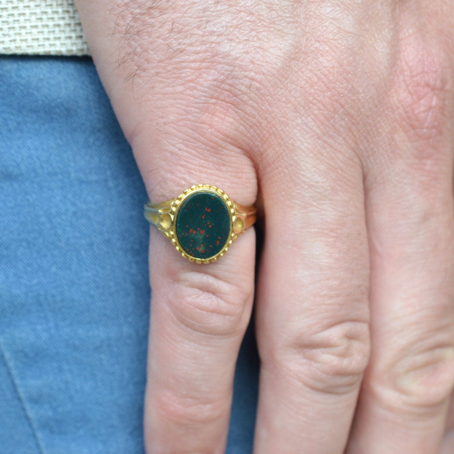 Victorian 18ct gold bloodstone signet ring on a hand, showcasing its ornate design and vibrant stone.
