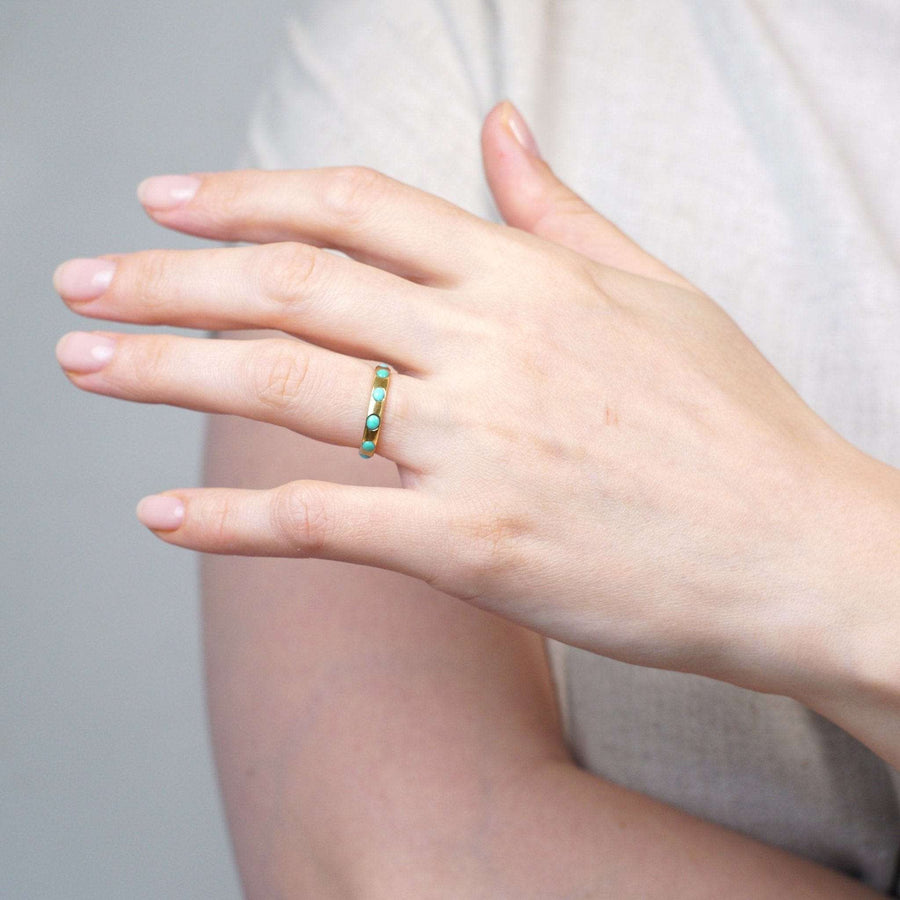 Victorian 18ct gold eternity ring with turquoise stones worn on a hand.
